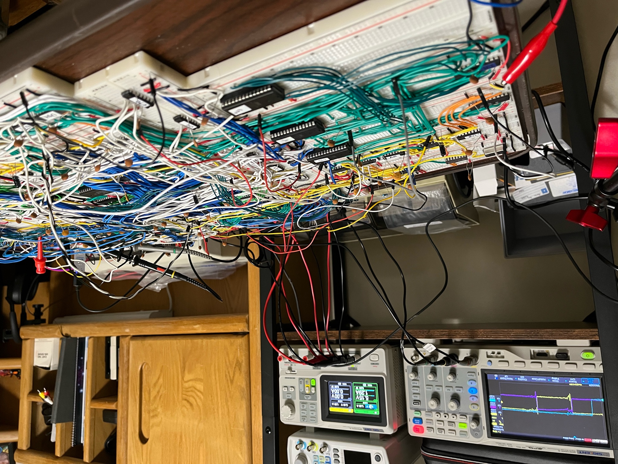 The bench at the end of the night. Ten breadboards of DINO with the scope probes still clipped on. The supply reads 5.15 V at 1.29 A, and the Siglent is still holding the last capture.