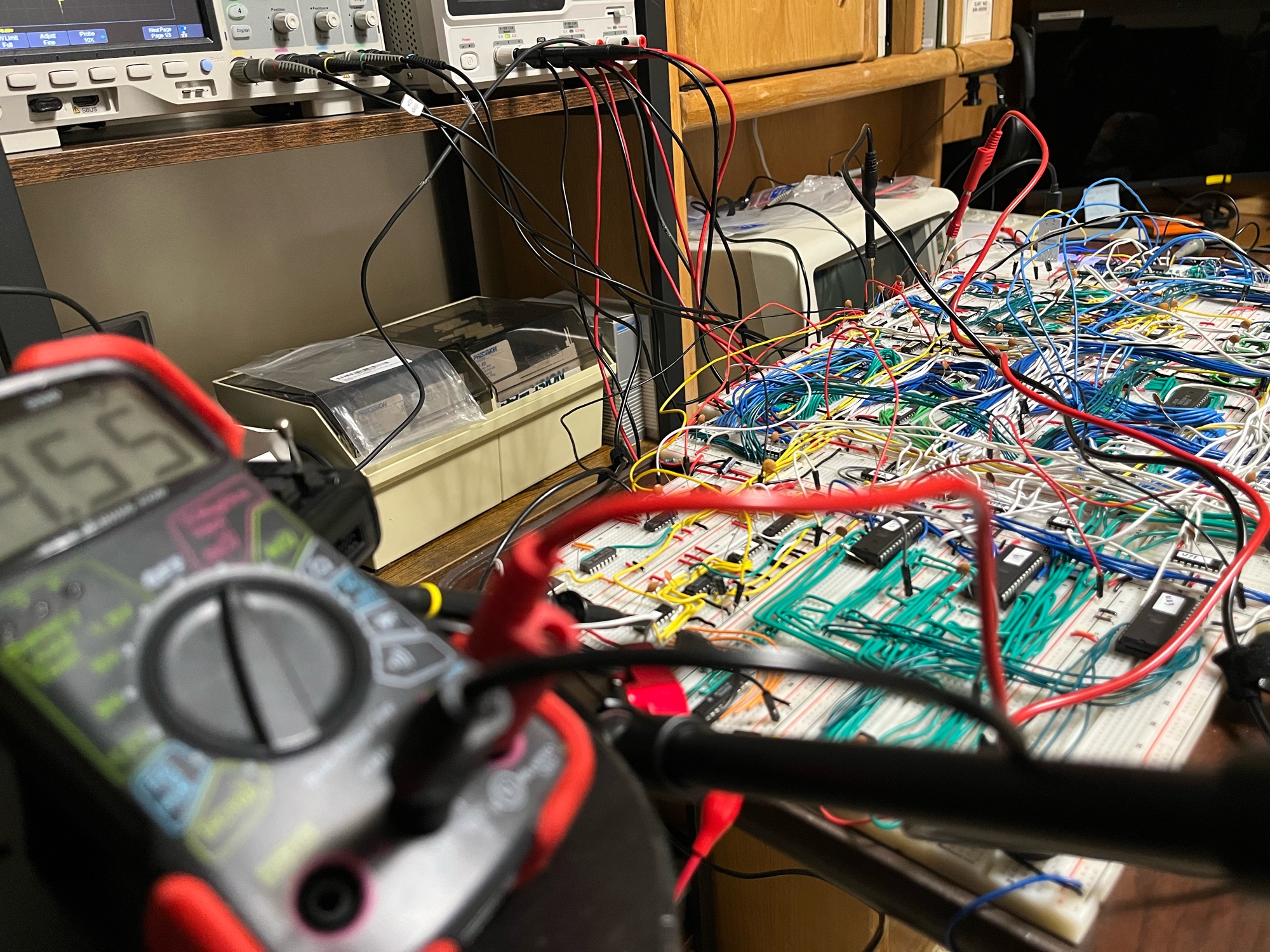The bench at the end of the day. DMM on the halted machine, scope probes all over the MDR and memory boards.