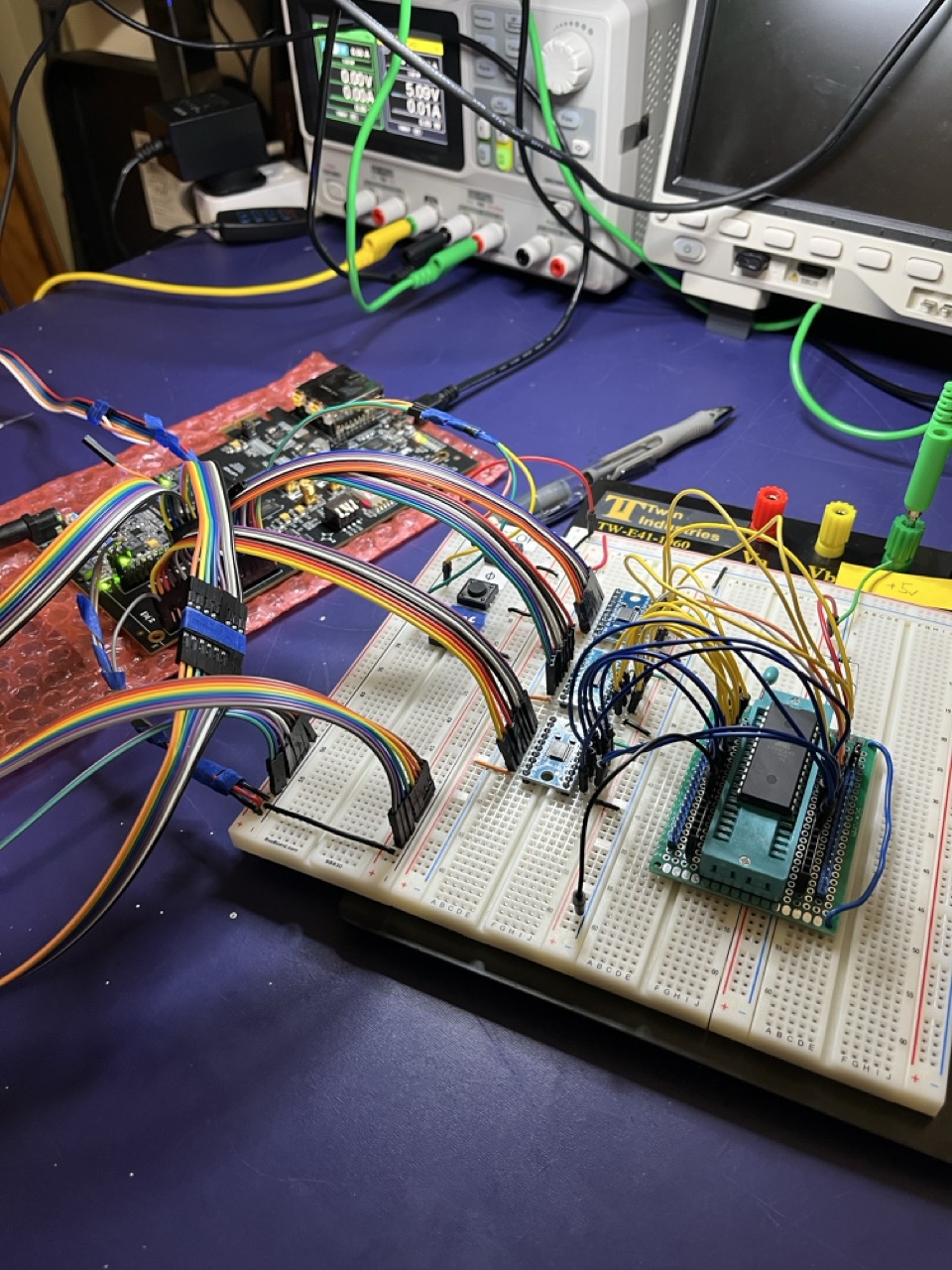 The external ROM rig, January 2026. ECP5-5G Versa on the bubble wrap, AT28C64B on a ZIF adapter at the right, HW-221 level shifter boards in between.